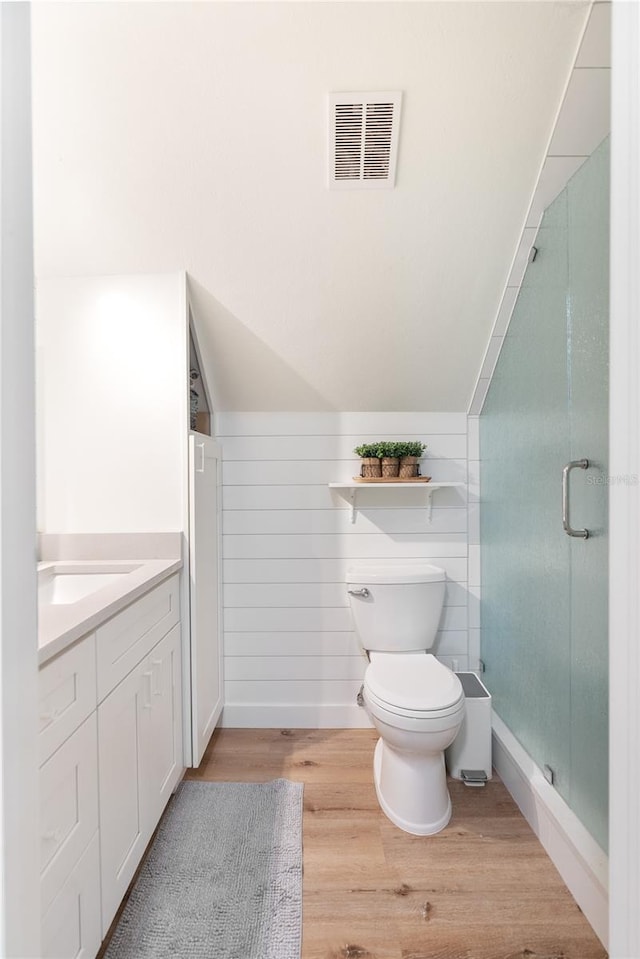 bathroom with wood-type flooring, an enclosed shower, wood walls, vanity, and toilet