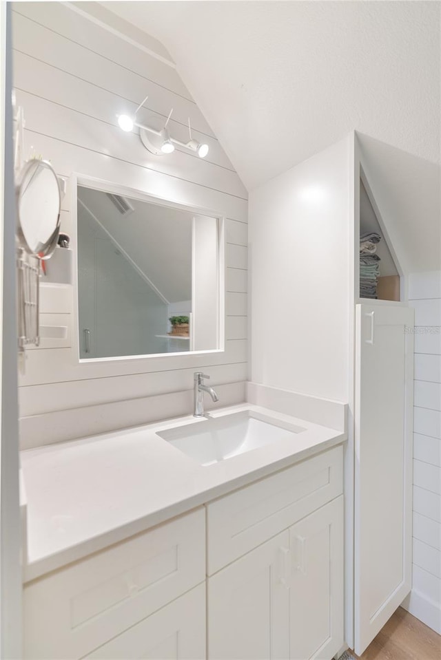 bathroom featuring wood-type flooring, vanity, and vaulted ceiling