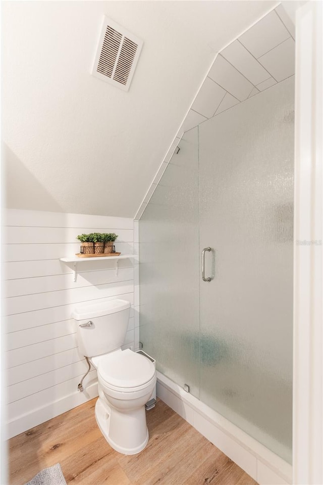 bathroom featuring hardwood / wood-style flooring, lofted ceiling, toilet, and an enclosed shower