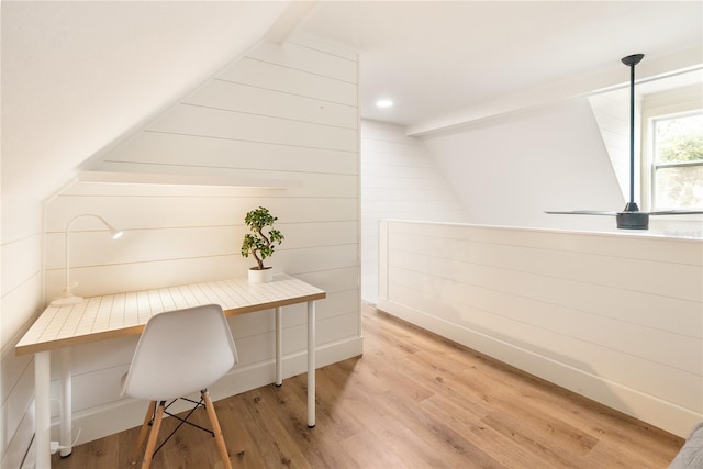 office area featuring vaulted ceiling with beams, light hardwood / wood-style floors, and wooden walls