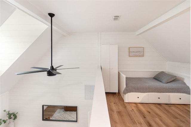 bedroom with ceiling fan, vaulted ceiling with beams, wooden walls, and light hardwood / wood-style floors