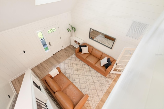 living room featuring wood-type flooring, wood walls, and high vaulted ceiling