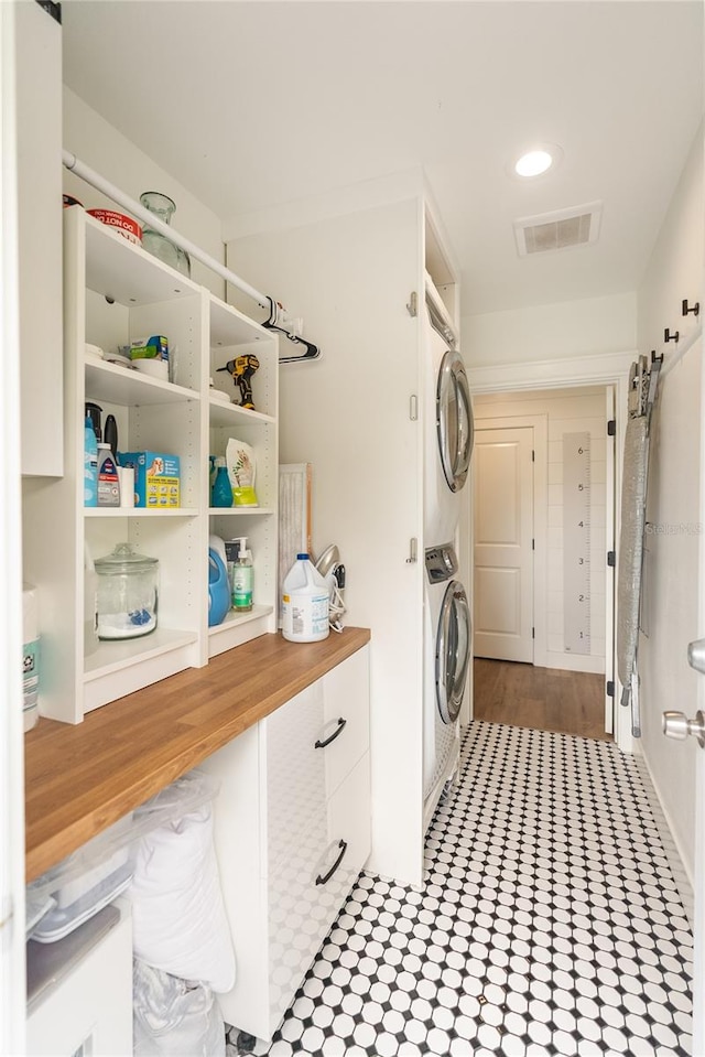 clothes washing area featuring stacked washer and clothes dryer and light hardwood / wood-style flooring