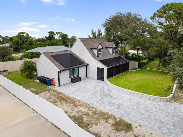 view of front of house with a front yard, a patio area, and solar panels