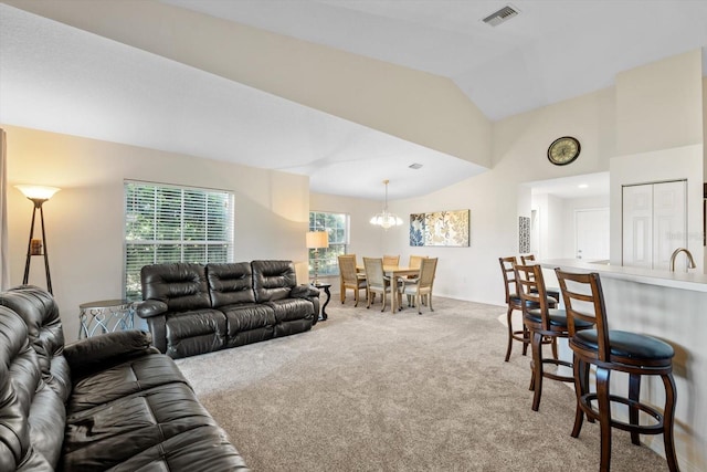 carpeted living room with vaulted ceiling, sink, and a notable chandelier