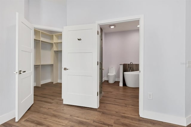 unfurnished bedroom with connected bathroom, hardwood / wood-style floors, a walk in closet, and a closet