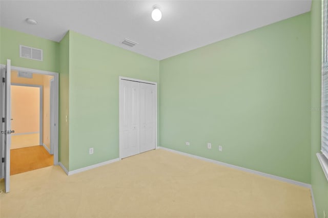 unfurnished bedroom featuring a closet and light colored carpet