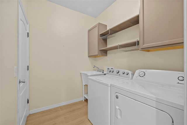 clothes washing area featuring cabinets, light hardwood / wood-style floors, and independent washer and dryer