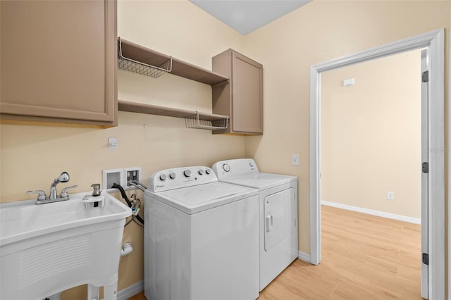 laundry room featuring cabinets, sink, light hardwood / wood-style floors, and washing machine and dryer