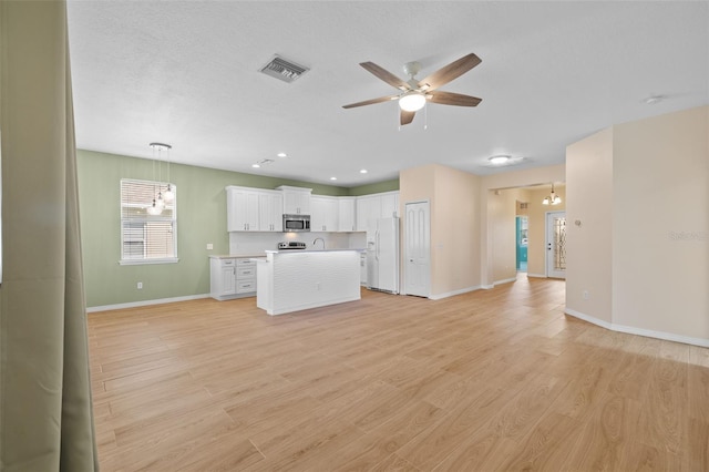 unfurnished living room featuring light wood-type flooring, ceiling fan with notable chandelier, a textured ceiling, and sink