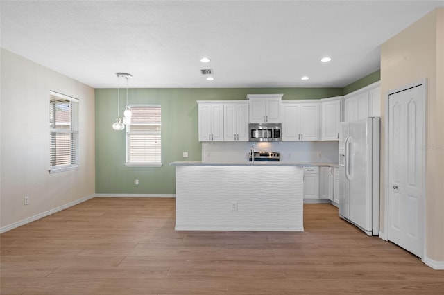 kitchen with an island with sink, decorative light fixtures, white cabinetry, stainless steel appliances, and light wood-type flooring