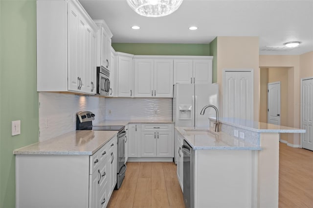 kitchen featuring white cabinets, sink, stainless steel appliances, light hardwood / wood-style floors, and decorative backsplash