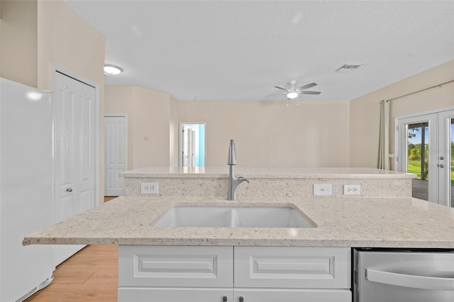 kitchen with white cabinetry, ceiling fan, white fridge, and sink