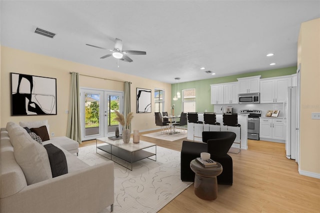 living room featuring ceiling fan, light hardwood / wood-style flooring, and french doors