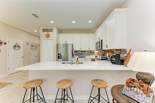 kitchen with stainless steel appliances, white cabinets, kitchen peninsula, and sink