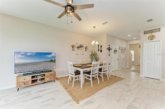 dining room with ceiling fan with notable chandelier and light hardwood / wood-style floors