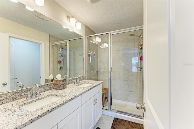 bathroom with walk in shower, vanity, tile patterned flooring, and a textured ceiling