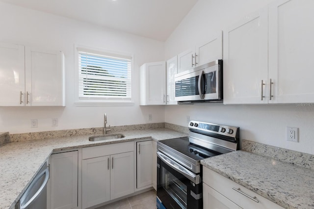 kitchen with light stone counters, sink, white cabinets, lofted ceiling, and stainless steel appliances