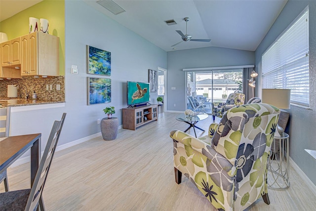 living room featuring sink, ceiling fan, and vaulted ceiling