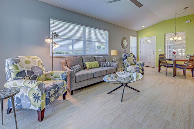 living room featuring ceiling fan with notable chandelier and vaulted ceiling