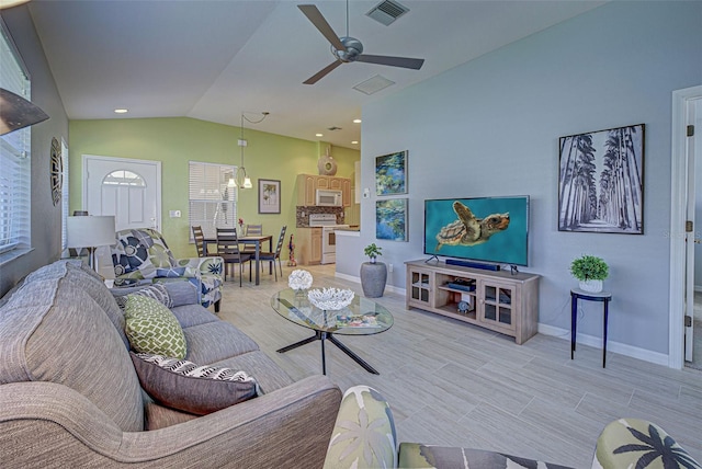 living room with ceiling fan with notable chandelier, lofted ceiling, and light hardwood / wood-style flooring