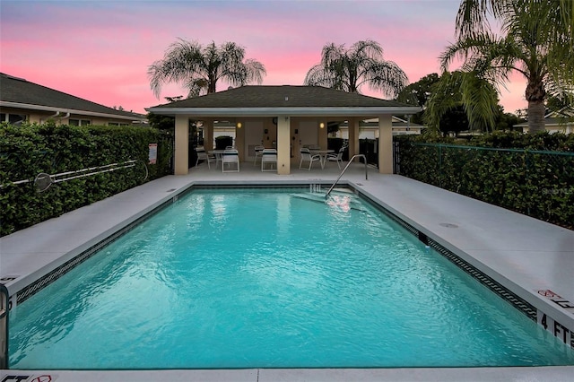 pool at dusk featuring a patio area