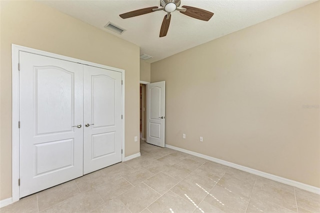 unfurnished bedroom featuring light tile patterned floors, a textured ceiling, a closet, and ceiling fan