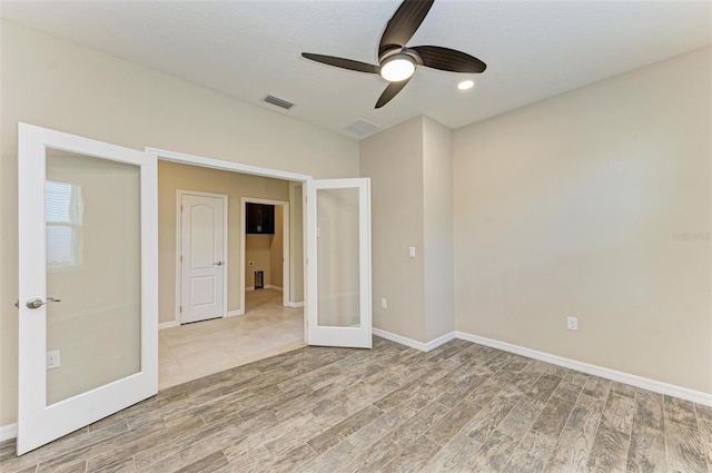 unfurnished room featuring french doors, hardwood / wood-style flooring, a textured ceiling, and ceiling fan