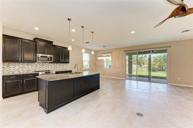 kitchen featuring sink, appliances with stainless steel finishes, a healthy amount of sunlight, and an island with sink