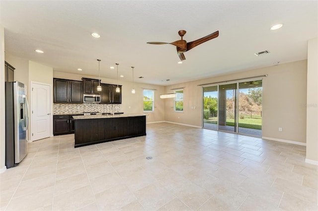 kitchen with decorative backsplash, appliances with stainless steel finishes, pendant lighting, and plenty of natural light