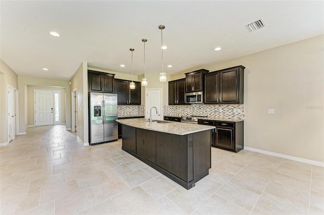 kitchen featuring appliances with stainless steel finishes, sink, an island with sink, pendant lighting, and decorative backsplash