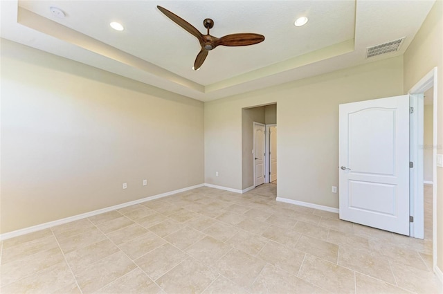 unfurnished room with ceiling fan and a raised ceiling