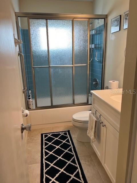 full bathroom with enclosed tub / shower combo, vanity, tile patterned flooring, and toilet