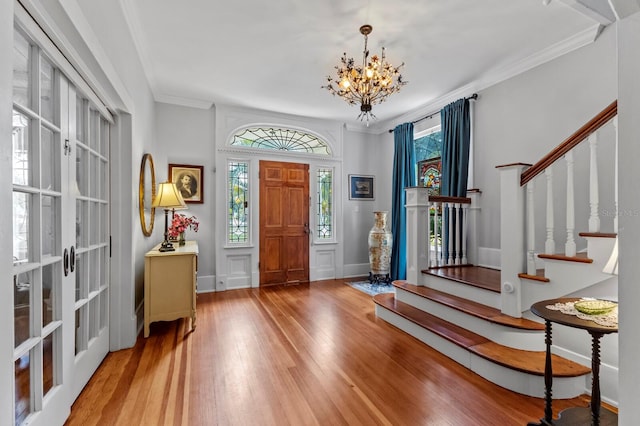 entrance foyer with a notable chandelier, ornamental molding, and hardwood / wood-style flooring