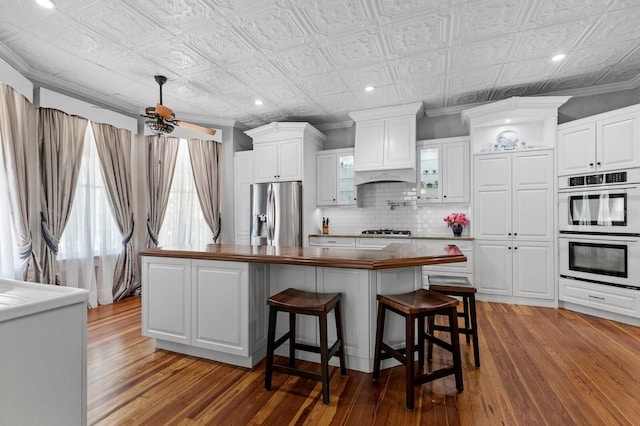 kitchen with stainless steel appliances, white cabinetry, a kitchen island, and hardwood / wood-style floors