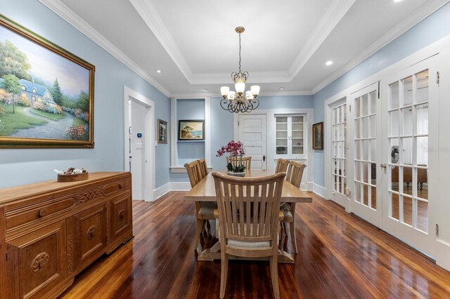 dining room with an inviting chandelier, ornamental molding, a tray ceiling, and dark hardwood / wood-style floors