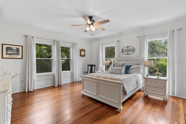 bedroom featuring multiple windows, crown molding, hardwood / wood-style floors, and ceiling fan