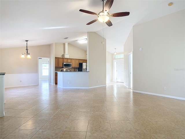 unfurnished living room featuring ceiling fan with notable chandelier, vaulted ceiling, and light tile patterned floors