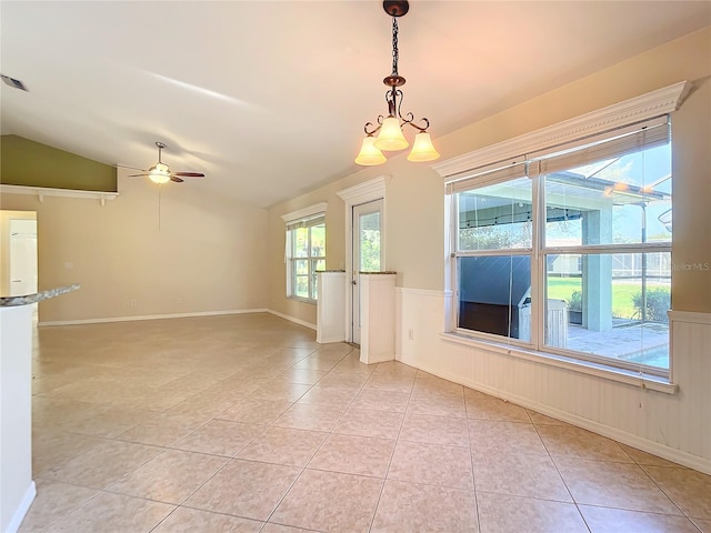 empty room featuring ceiling fan with notable chandelier, lofted ceiling, and light tile patterned flooring