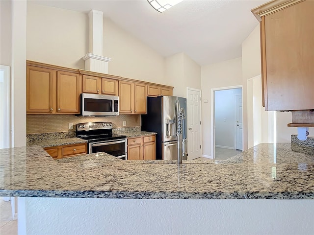 kitchen featuring kitchen peninsula, light stone countertops, stainless steel appliances, and high vaulted ceiling