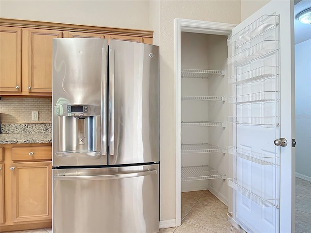 kitchen featuring light stone countertops, decorative backsplash, light tile patterned flooring, and stainless steel fridge with ice dispenser