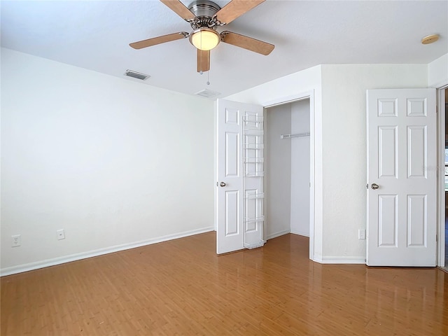 unfurnished bedroom featuring ceiling fan, a closet, and hardwood / wood-style flooring