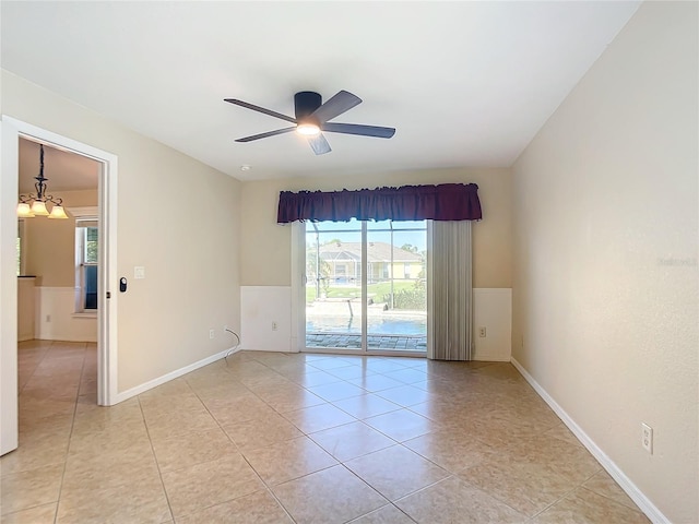 empty room with ceiling fan with notable chandelier and light tile patterned flooring