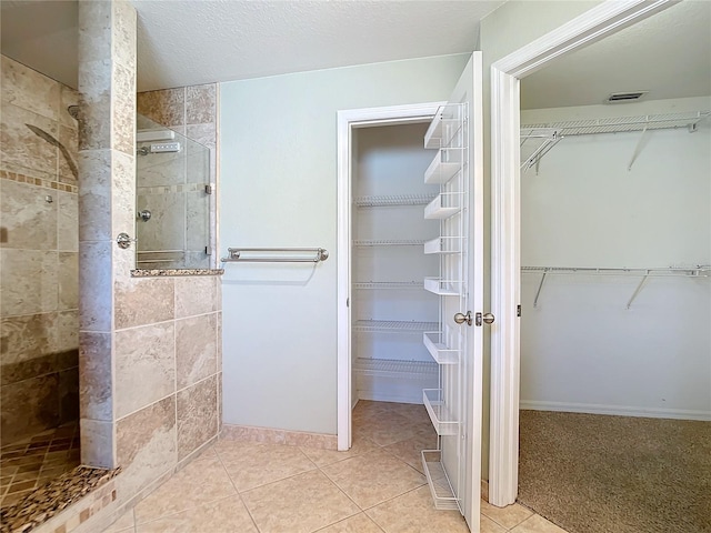 bathroom with a tile shower and tile patterned flooring