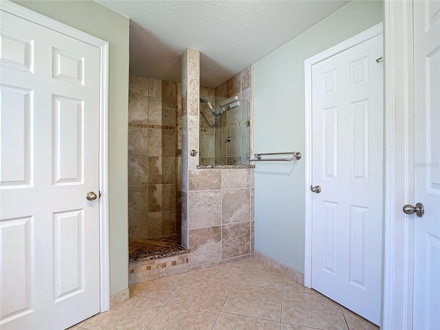 bathroom with a textured ceiling, a tile shower, and tile patterned floors