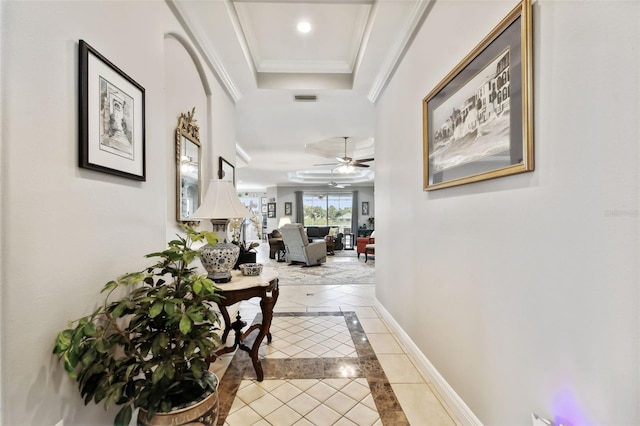 hall with a tray ceiling, light tile patterned floors, and crown molding