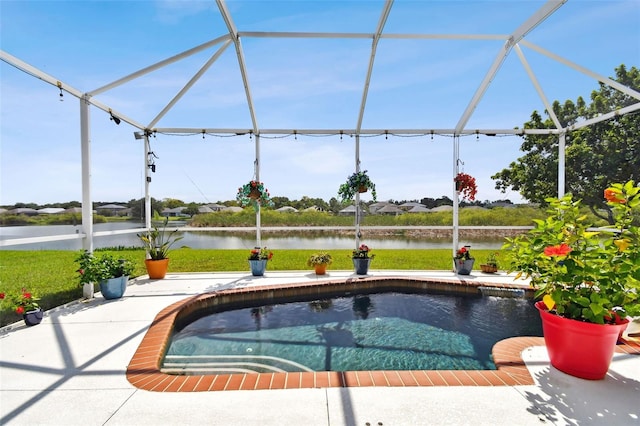 view of pool with glass enclosure, a water view, and a patio area