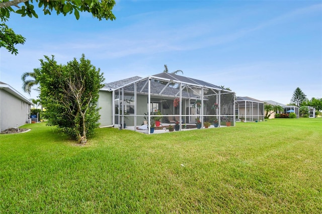 back of house featuring glass enclosure and a yard