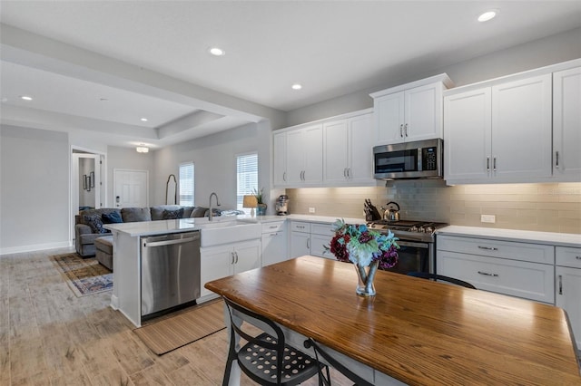 kitchen featuring white cabinetry, sink, tasteful backsplash, light hardwood / wood-style flooring, and appliances with stainless steel finishes