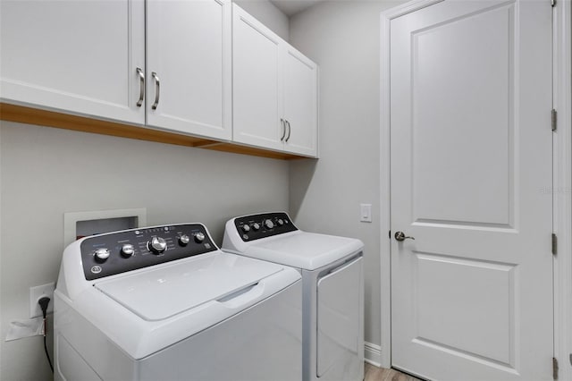 laundry room with cabinets, light hardwood / wood-style flooring, and washer and clothes dryer